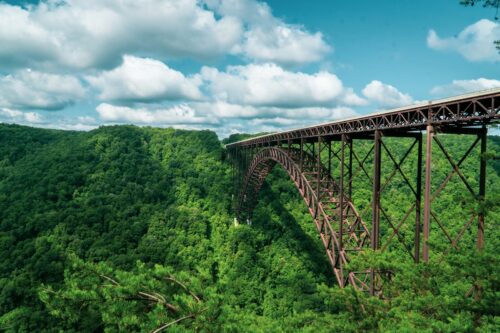West Virginia gray metal bridge over green trees under white clouds and blue sky during daytime