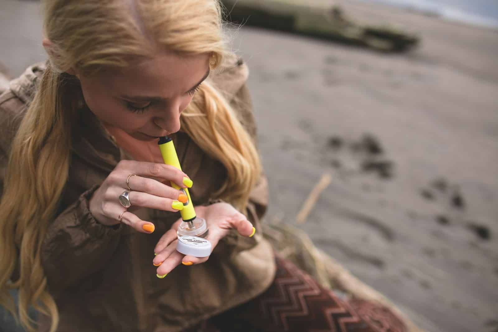 a woman holding a bottle of liquid, distillate vs live resin